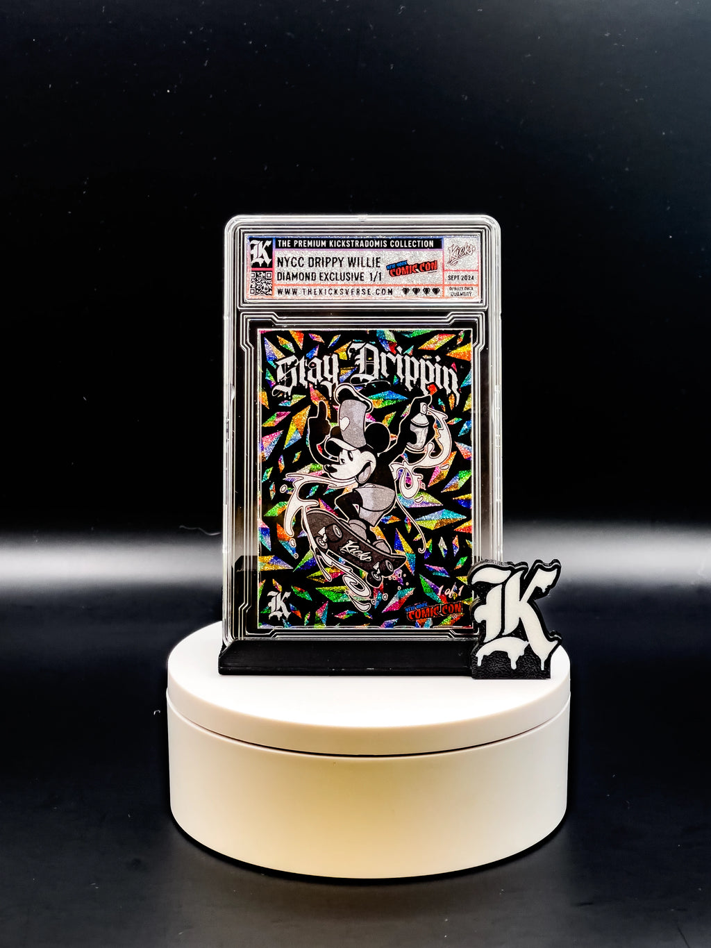 Collectible card with colorful design and 'Stay Drippin' text on a white stand against a black background