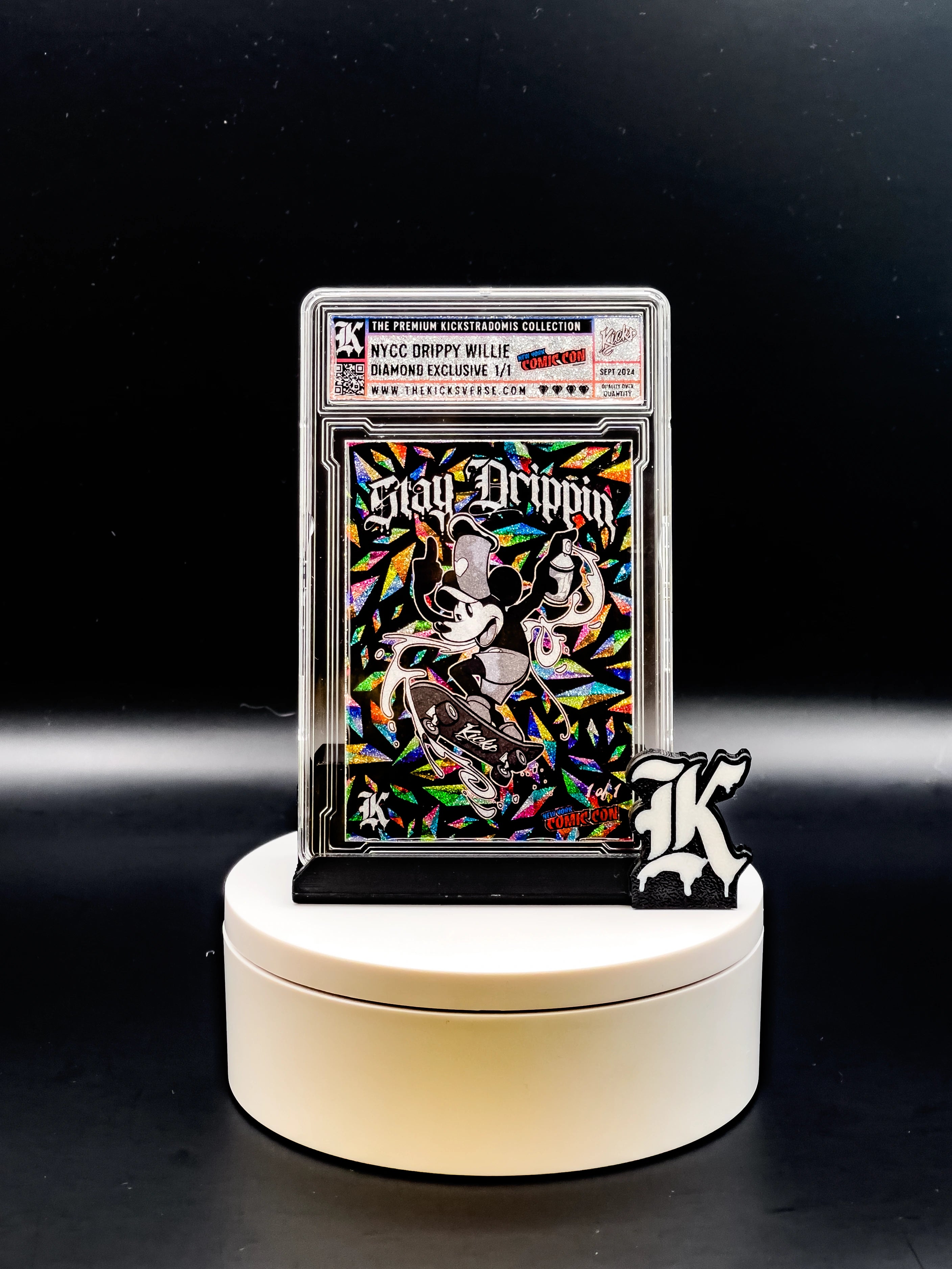 Collectible card with colorful design and 'Stay Drippin' text on a white stand against a black background
